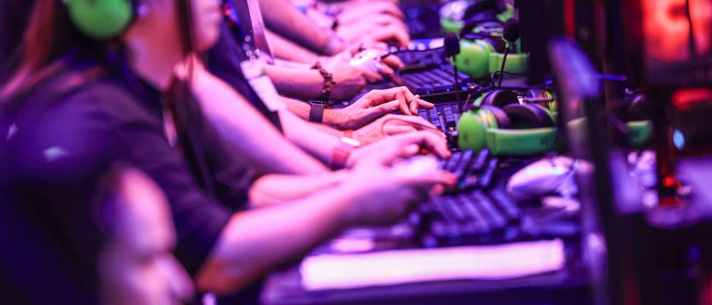 Computerspielerinnen und Computerspieler sitzen im August 2024 bei der Messe Gamescom vor Bildschirmen.