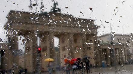 Blick von Westen auf das Brandenburger Tor durch eine von Regentropfen bedeckte Autoscheibe.
