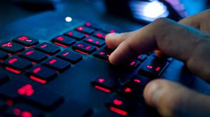 Ein Mann sitzt am Rechner und tippt auf einer Tastatur. 