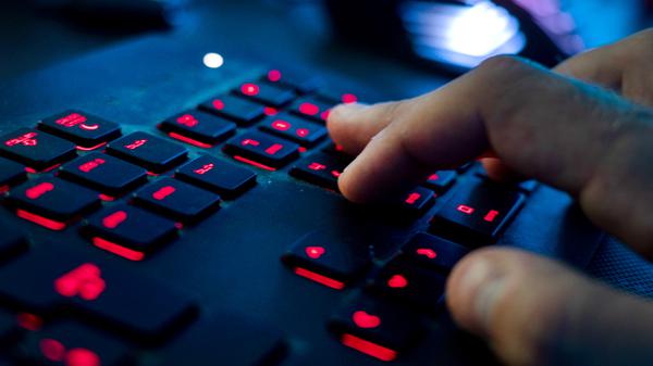 Ein Mann sitzt am Rechner und tippt auf einer Tastatur.