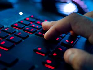 Ein Mann sitzt am Rechner und tippt auf einer Tastatur.