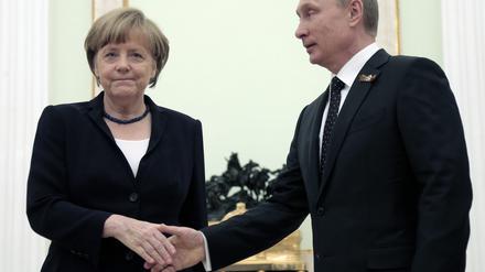 Die ehemalige Bundeskanzlerin Angela Merkel (l.) und der russische Präsident Wladimir Putin (r.) schütteln sich die Hände während ihrer Gespräche im Kreml. 