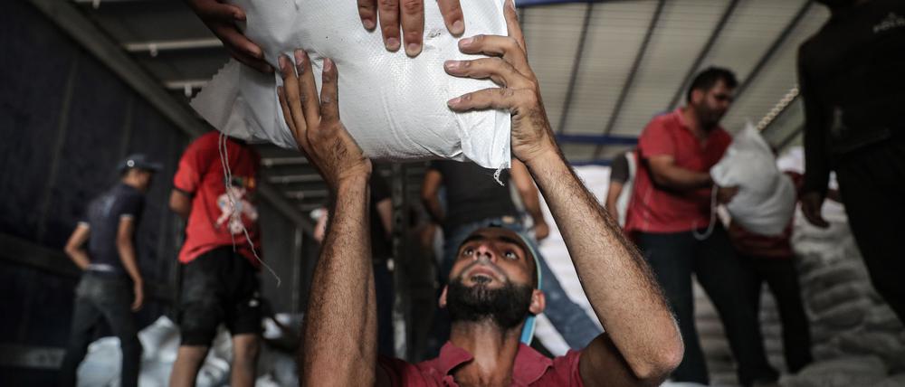 ARCHIV - 30.06.2021, Syrien, Bab Al-Hawa: Syrer lagern Pakete mit Lebensmitteln des Welternährungsprogramms der Vereinten Nationen (WFP), die zuvor mit LKWs aus der Türkei in den Nordwesten Syriens gebracht worden sind. Hilfsorganisationen und Menschenrechtler fordern vom US-Sicherheitsrat, die grenzüberschreitende Hilfe für notleidende Menschen in Syrien zu verlängern.