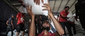 ARCHIV - 30.06.2021, Syrien, Bab Al-Hawa: Syrer lagern Pakete mit Lebensmitteln des Welternährungsprogramms der Vereinten Nationen (WFP), die zuvor mit LKWs aus der Türkei in den Nordwesten Syriens gebracht worden sind. Hilfsorganisationen und Menschenrechtler fordern vom US-Sicherheitsrat, die grenzüberschreitende Hilfe für notleidende Menschen in Syrien zu verlängern.
