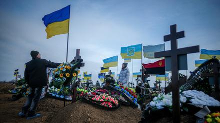 Anna, die Ehefrau eines vor zwei Monaten getöteten Soldaten, und der Vater Oleksandr stellen auf dem Friedhof der Hafenstadt Odessa die ukrainische Nationalflagge am Grab ihres Ehemannes auf. 