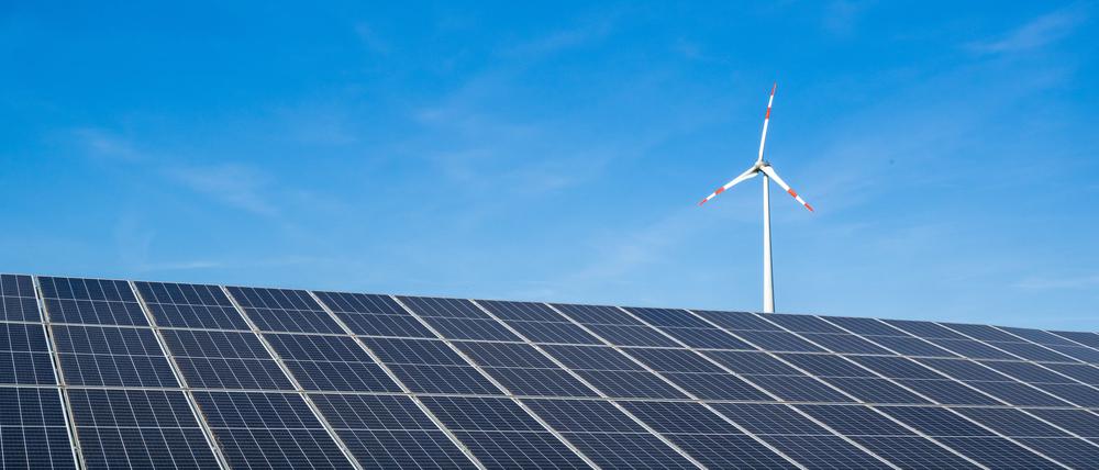 Ein Windrad steht hinter einem Solarfeld unweit der Autobahn.