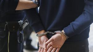 Ein Mann trägt Handschellen und wird von einem Polizisten abgeführt. (Symbolbild)