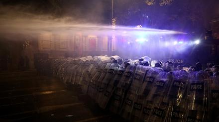 Polizeibeamte setzen einen Wasserwerfer ein.