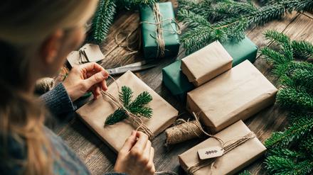 Eine Frau verpackt ein Weihnachtsgeschenk. 