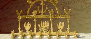 Eine Menora aus Baghdad (um 1900), Objekt aus der Ausstellung „The Vicious Circle“ vom National Holocaust Centre and Museum London. Einige ihrer Symbole sind aus dem Islam entliehen: der Halbmond, die Vögel und die Hände (Hamsas). 