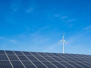 Ein Windrad steht hinter einem Solarfeld unweit der Autobahn. 