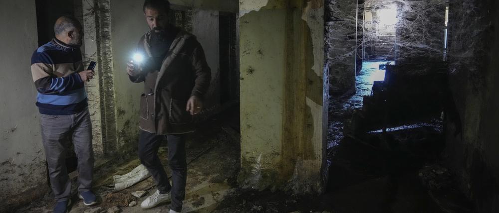 Zwei Männer inspizieren mit ihren Taschenlampen einen Korridor des berüchtigten Militärgefängnisses Saydnaya nördlich von Damaskus. Tausende von Insassen wurden nach dem Sturz des Regimes von Bashar al-Assad durch die Rebellen am Sonntag freigelassen, und einige hoffen, dort ihre Angehörigen zu finden.
