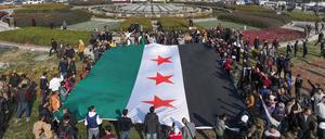 Menschen halten eine Flagge der syrischen Revolution am Umayyad-Platz in Damaskus.