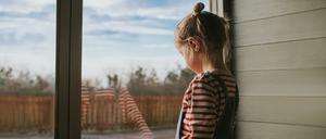 Ein kleines Mädchen schaut aus dem Fenster. Schon vermeintlich „harmlose“ Konflikte können Kinder stark belasten – oft ohne dass Eltern es merken. 