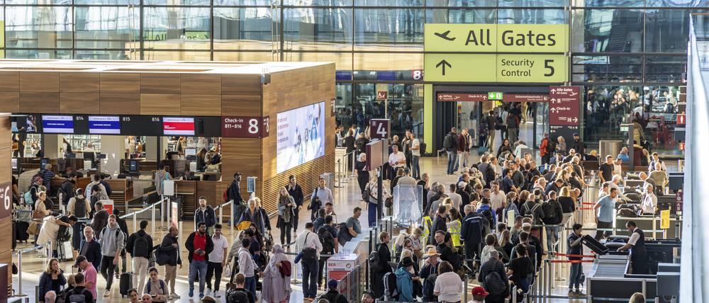 Passagiere im Terminal 1 warten vor dem Abflug auf Check-in und Sicherheitskontrolle.