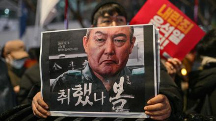 Ein Demonstrant hält ein Plakat mit einem Bild des südkoreanischen Präsidenten Yoon Suk Yeol. 