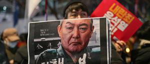 Ein Demonstrant hält ein Plakat mit einem Bild des südkoreanischen Präsidenten Yoon Suk Yeol. 