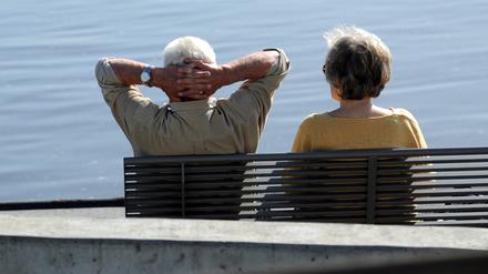 Ein Senioren-Paar sitzt auf einer Bank an der Elbe.