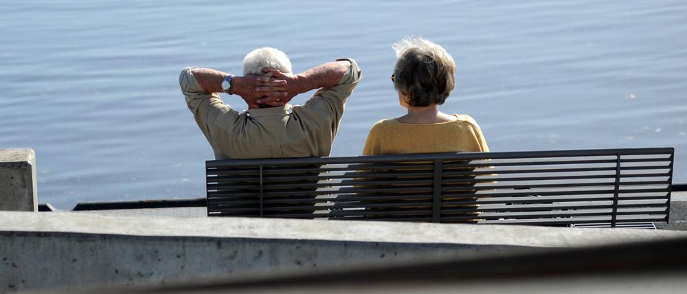 Ein Senioren-Paar sitzt auf einer Bank an der Elbe.