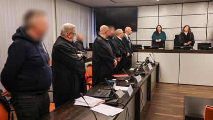 10.12.2024, Nordrhein-Westfalen, Wuppertal: Die Angeklagten und ihre Anwälte stehen beim Einzug der Richterin Birgit Neubert (r) auf. In Wuppertal hat der Prozess wegen eines Erpressungsversuchs gegen die Familie von Ex-Formel-1-Weltmeister Michael Schumacher begonnen. Angeklagt sind drei 30 bis 53 Jahre alte Männer. Dem Haupttäter wird versuchte Erpressung in einem besonders schweren Fall vorgeworfen, den beiden anderen Beihilfe dazu.