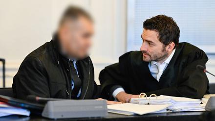 Der Angeklagte spricht im Verhandlungssaal mit seinem Anwalt. 