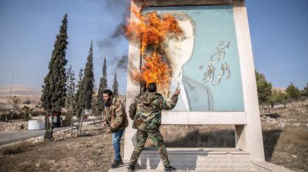 Ein Mann entzündet ein Bild des ehemaligen syrischen Präsidenten Bashar al-Assad in der Nähe der syrischen Grenze zum Libanon.