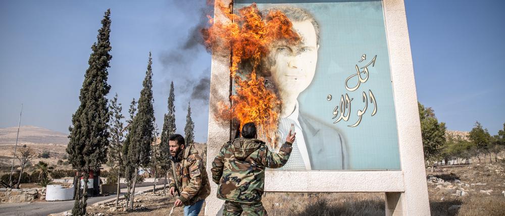 Ein Mann entzündet ein Bild des ehemaligen syrischen Präsidenten Bashar al-Assad in der Nähe der syrischen Grenze zum Libanon.