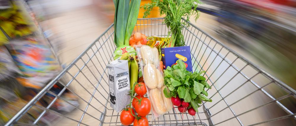 Ein mit Lebensmittel gefüllter Einkaufswagen wird durch einen Supermarkt geschoben.