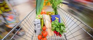 Ein mit Lebensmittel gefüllter Einkaufswagen wird durch einen Supermarkt geschoben.