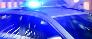 Ein Streifenwagen der Polizei steht mit eingeschaltetem Blaulicht auf der Straße. 