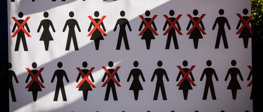 Eine Arbeitnehmerin hält ein Protestplakat mit durchgestrichenen Pictogrammen in den Händen.
