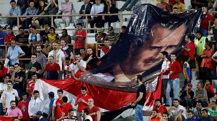 Syrische Fußball-Fans halten 2018, bei einem Spiel gegen Südkorea, ein Banner mit einem Bild von Baschar al-Assad in die Höhe.