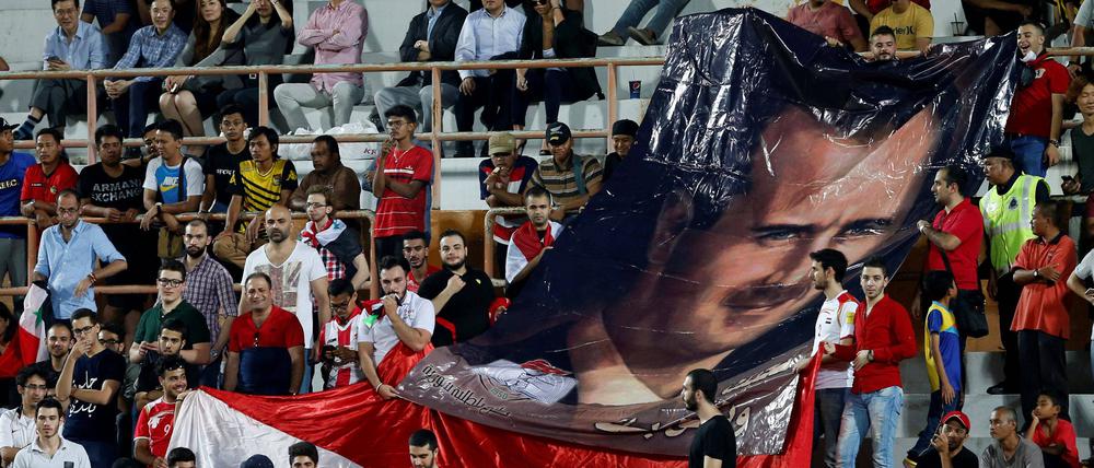 Syrische Fußball-Fans halten 2018, bei einem Spiel gegen Südkorea, ein Banner mit einem Bild von Baschar al-Assad in die Höhe.
