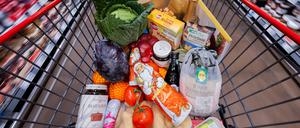 Ein voller Einkaufswagen mit einer Polnischen Ente, Gemüse, Obst, Christstollen, Knödel, Sekt, Wein, Pralinen und Schokoladen-Weihnachtsmännern wird an Regalen vorbei in einem Supermarkt geschoben (Symbolbild).