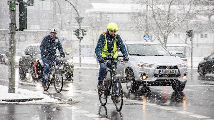 Autos und Fahrradfaher unterm Schneefall in Berlin am 16. Januar 2024. 