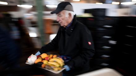 25.11.2024, Nordrhein-Westfalen, Oberhausen: Ein Tafel-Mitarbeiter trägt ein Tablet mit Obst.