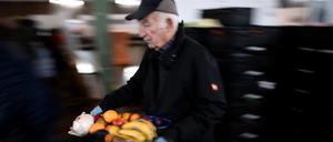 25.11.2024, Nordrhein-Westfalen, Oberhausen: Ein Tafel-Mitarbeiter trägt ein Tablet mit Obst.