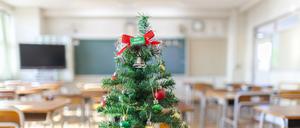 Ein Weihnachtsbaum steht in einem Klassenzimmer.