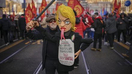 Ein Demonstrant hält während eines landesweiten Generalstreiks eine Puppe, die die italienische Ministerpräsidentin Giorgia Meloni darstellt, mit einem Schild, auf dem in italienischer Sprache zu lesen ist: „Amnestie für Steuerhinterzieher, Geld für Waffen, Geld für die Brücke, Kürzungen im Gesundheitswesen, Millionen, die in Albanien weggeworfen werden“. 