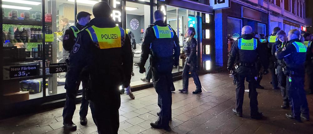 Einsatzkräfte der Polizei stehen vor einem Friseursalon in Hamburg-Billstedt.