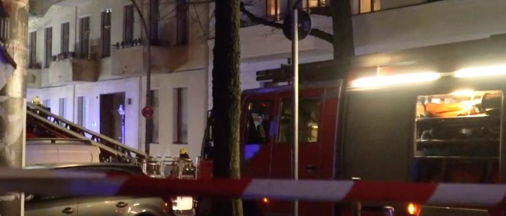 Feuerwehrleute arbeiten an einem brennenen Fenster in einem Mehrfamilienhaus in Neukölln.