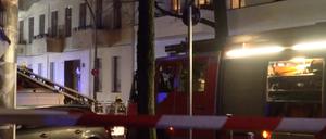 Feuerwehrleute arbeiten an einem brennenen Fenster in einem Mehrfamilienhaus in Neukölln.