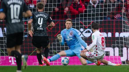 Kölns Denis Huseinbasic (r) trifft gegen FCN-Torhüter Jan Reichert (M) zum 3:0. 