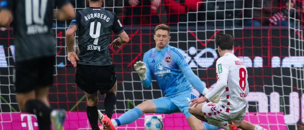 Kölns Denis Huseinbasic (r) trifft gegen FCN-Torhüter Jan Reichert (M) zum 3:0. 