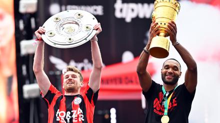 Sind sind noch im Geschäft. Leverkusens Torhüter Lukas Hradecky (l) und Leverkusens Jonathan Tah präsentieren bei der Meisterfeier in der BayArena die Meisterschale und den Pokal. 