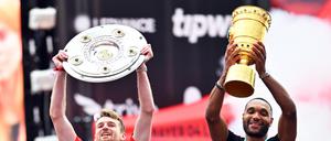 Sind sind noch im Geschäft. Leverkusens Torhüter Lukas Hradecky (l) und Leverkusens Jonathan Tah präsentieren bei der Meisterfeier in der BayArena die Meisterschale und den Pokal. 