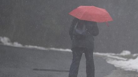 Eine Frau geht mit einem Regenschirm durch den Schnee (Symbolbild).