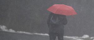 Eine Frau geht mit einem Regenschirm durch den Schnee (Symbolbild).