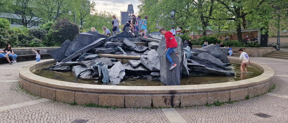 Kinder spielen auf dem Ammonitenbrunnen des Bildhauers Volker Bartsch auf dem Olof-Palme-Platz am Berliner Zoo und Aquarium.