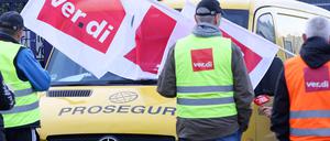 Teilnehmer eines Streiks stehen vor einer Niederlassung von Prosegur in Hamburg an einem Geldtransporter (Archivbild).